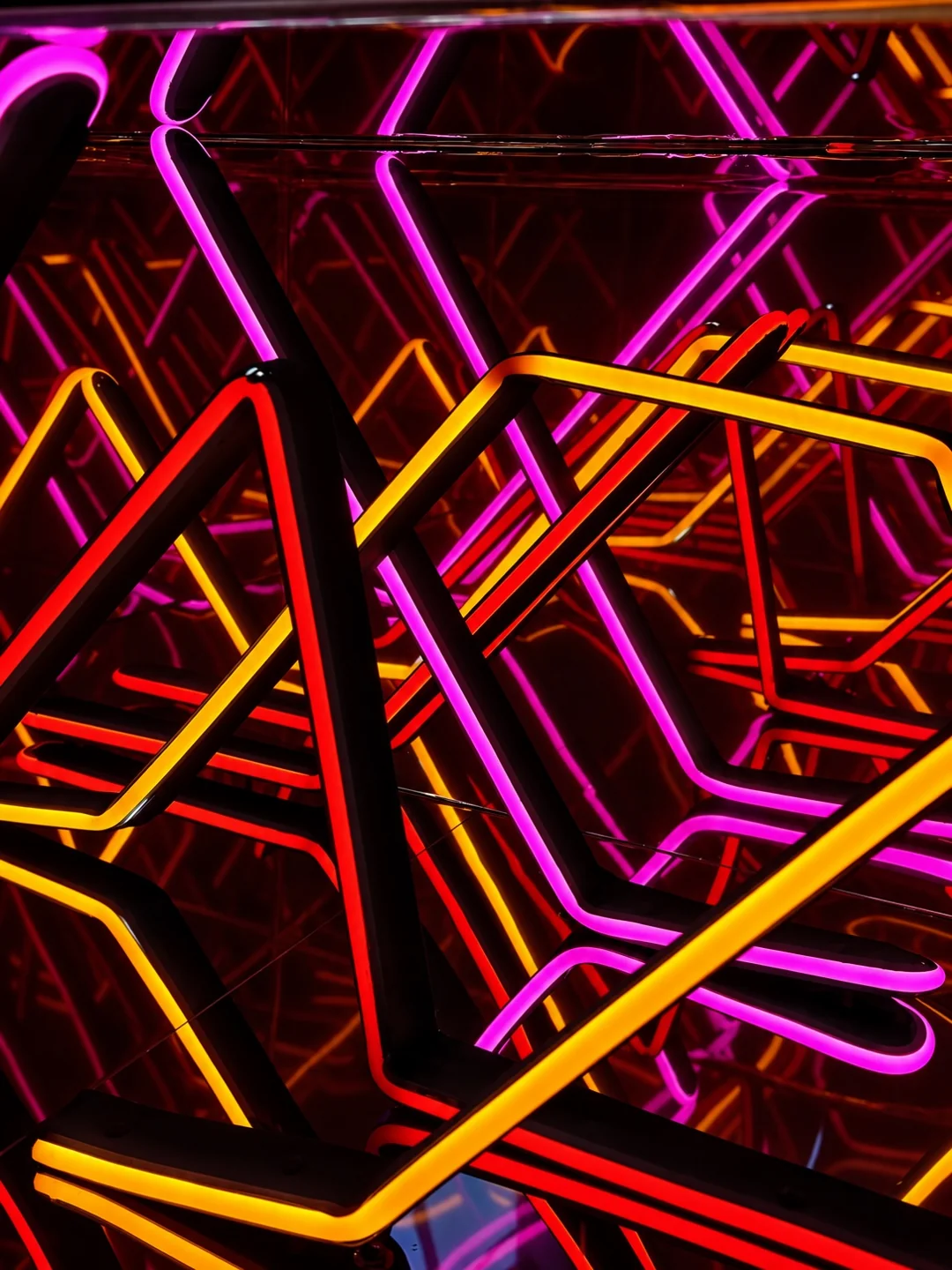 Close-up of pink and yellow LED patterns reflected inside a glass Infinity Mirror table